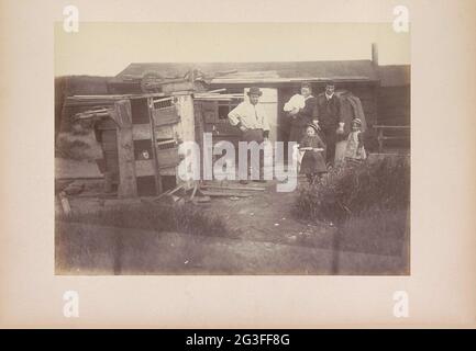 Résidents d'une maison en bois à Amsterdam; d'Amsterdam. Deux hommes, une femme avec un bébé, deux filles et un chien devant une maison en bois, Amsterdam. Sur la gauche une grange avec sur le dessus des lattes en bois et une brouette à l'envers. Banque D'Images