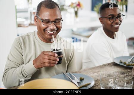 Heureux père noir buvant yerba mate pendant le déjeuner à la maison - foyer principal sur le visage de l'homme Banque D'Images