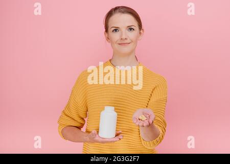 Belle femme au foyer tient tube avec des vitamines dans la main et donner des pilules à quelqu'un ensemble regarde le traitement de caméra et la prévention des maladies med Banque D'Images