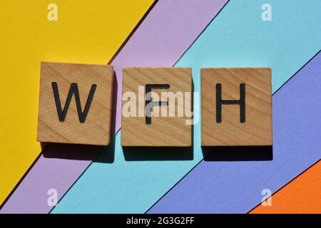 WFH, acronyme de Work from Home, en lettres de l'alphabet en bois isolées sur fond coloré Banque D'Images