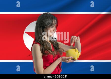 Économie en Corée du Nord accumuler et économiser de l'argent en Corée du Nord une femme mettant de l'argent de pièce dans la banque de piggy pour économiser de l'argent et planifier le financement Banque D'Images