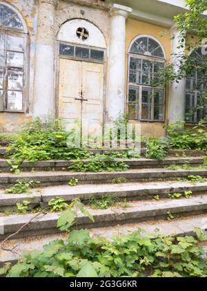 Vieux beau bâtiment abandonné dans un jardin vert avec des escaliers de mousse. Banque D'Images