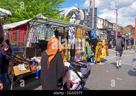 Textiles et vêtements africains à vendre sur le marché des commerçants les gens de décrochage shopping dans Walthamstow High Street Londres E17 Angleterre Royaume-Uni KATHY DEWITT Banque D'Images