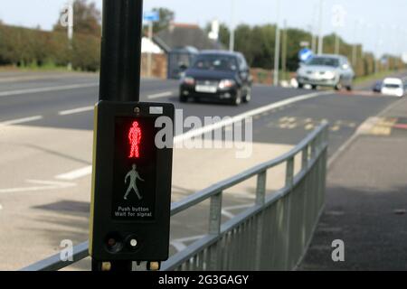 A78 Stevenston, North Ayrshire, Écosse. Royaume-Uni enfants à vélo traversant la route du tronc en utilisant le Pelican Crossing. Un passage à niveau en pélican est le nom britannique et irlandais d'un type de passage à niveau pour piétons, qui comprend une paire de pôles chacun avec un ensemble standard de feux de signalisation faisant face à la circulation venant en sens inverse, un bouton-poussoir et deux pictogrammes lumineux de couleur faisant face au piéton de l'autre côté de la route. Banque D'Images