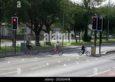 A78 Stevenston, North Ayrshire, Écosse. Royaume-Uni enfants à vélo traversant la route du tronc en utilisant le Pelican Crossing. Un passage à niveau en pélican est le nom britannique et irlandais d'un type de passage à niveau pour piétons, qui comprend une paire de pôles chacun avec un ensemble standard de feux de signalisation faisant face à la circulation venant en sens inverse, un bouton-poussoir et deux pictogrammes lumineux de couleur faisant face au piéton de l'autre côté de la route. Banque D'Images