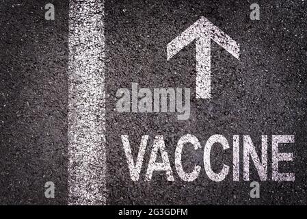 Mot vaccin écrit sur la route de l'asphalte avec flèche de direction, covid-19 concept de campagne de vaccination Banque D'Images