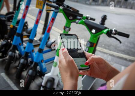 Une femme utilise une application pour retourner un e-scooter à une station de location à Londres, où, à partir du lundi 7 juin 2021, des scooters électriques sont disponibles à la location. Banque D'Images