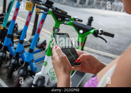 Une femme utilise une application pour retourner un e-scooter à une station de location à Londres, où, à partir du lundi 7 juin 2021, des scooters électriques sont disponibles à la location. Banque D'Images