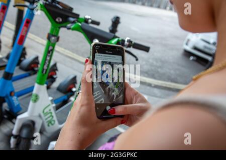 Une femme utilise une application pour retourner un e-scooter à une station de location à Londres, où, à partir du lundi 7 juin 2021, des scooters électriques sont disponibles à la location. Banque D'Images