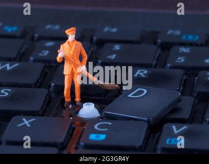Travailleur miniature avec balai travaillant sur le clavier Banque D'Images