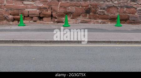 Trois cônes de signalisation en plastique vert à côté de la route contre le mur historique Banque D'Images