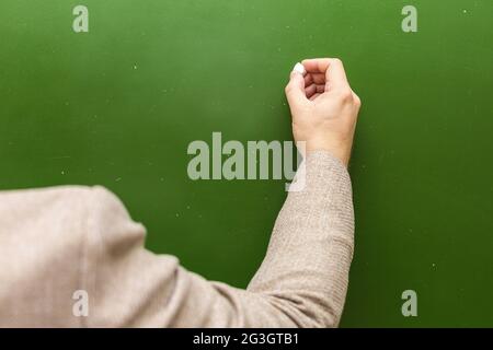 Un professeur de mathématiques écrit de la craie sur le tableau noir, dans l'espace de copie. Banque D'Images