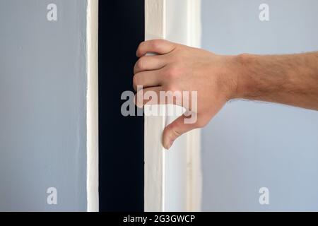 Man Hand ouvre la porte blanche d'une armoire bleue. Banque D'Images