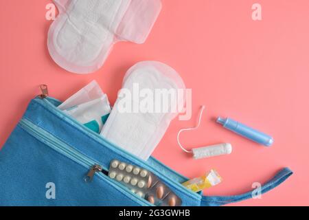 Trousse de toilette avec divers produits d'hygiène menstruelle et pilules pour femmes sur fond rose. Vue de dessus. Banque D'Images