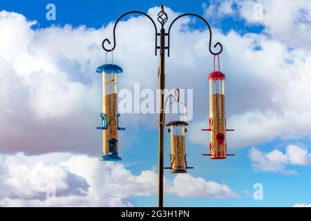 Trois mangeoires d'oiseaux accrochées à un poteau avec un fond de ciel de nuages Banque D'Images