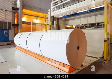 De gros rouleaux de papier sortent de la machine dans une usine de papeterie. Banque D'Images