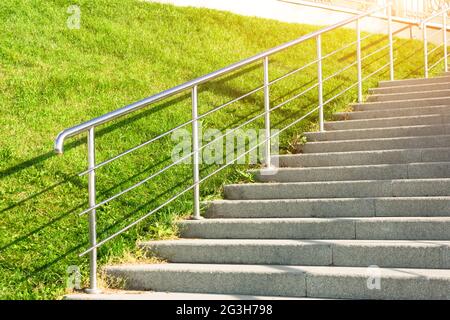 Escalier en pierre menant à la pente avec pelouse, avec métal brillant et garde-corps Banque D'Images