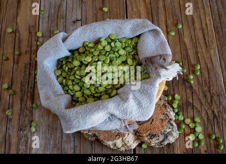 sac de petits pois verts sur une table en bois Banque D'Images