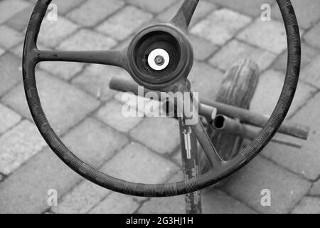 Photo en niveaux de gris en grand angle d'une vieille roue dans la rue Banque D'Images