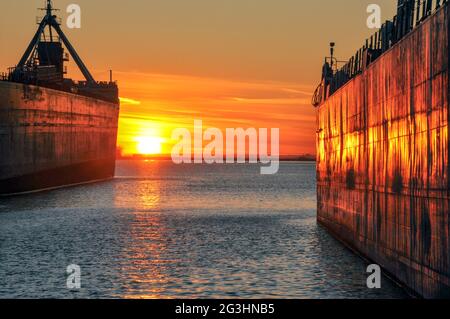 Deux navires de transport en vrac sont vus dans le port de Toronto, illuminant une orange flamboyante au coucher du soleil. Concept de transport maritime. Banque D'Images