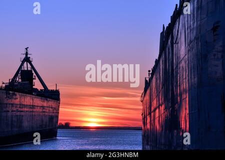 Deux navires de transport en vrac sont vus dans le port de Toronto, illuminant une orange flamboyante au coucher du soleil. Concept de transport maritime. Banque D'Images