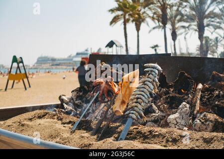 Une variété de fruits de mer cuisent sur un barbecue au feu de bois de fortune dans un restaurant sur la plage de Malagueta, Málaga, Espagne Banque D'Images