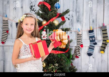 Une adolescente ouvre un cadeau de Noël près de l'arbre du nouvel an Banque D'Images