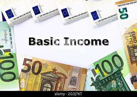 Photo TopView sur le thème du revenu de base universel. Les mots revenu de base sur papier, entourés de billets en euros Banque D'Images