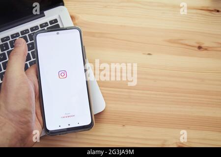 Madrid Espagne, juin 13 2021; mains tenant un appareil mobile intelligent avec le logo de l'application Instagram de la société sur l'écran et un ordinateur en t Banque D'Images