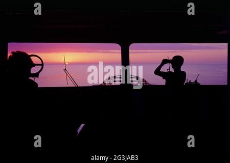 Les officiers de pont sur la montre pour observer. Temps calme, coucher de soleil sur la mer Banque D'Images