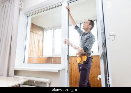 Le travailleur de la construction retire le ruban adhésif du cadre de fenêtre dans la maison Banque D'Images