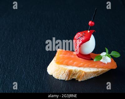 Un magnifique sandwich créatif est un en-cas traditionnel espagnol de tapas. Les tapas se composent de saumon, d'œuf de caille, de fromage à la crème, de feuilles de basilic, de poivre rouge, et Banque D'Images