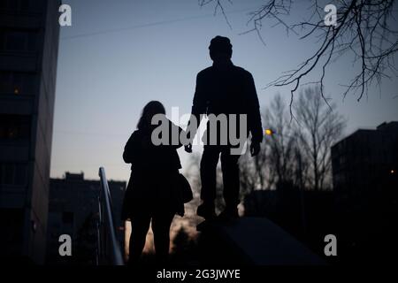 Silhouette d'une fille et d'un gars. Marchez la nuit. Les jeunes se reposent dans le noir. Rencontrer un gars et une fille. La silhouette d'un homme. Banque D'Images