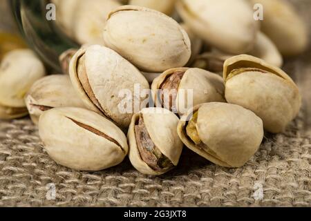 Pistaches disposées sur un toile de jute. Un en-cas savoureux consommé avec de la bière. Arrière-plan clair. Banque D'Images