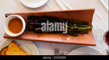 Les oignons calcottes sont servis sur une assiette avec une sauce Romesco - plat traditionnel catalan Banque D'Images