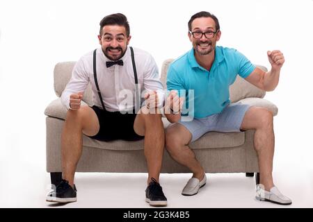 Deux hommes excités sitting on couch Banque D'Images