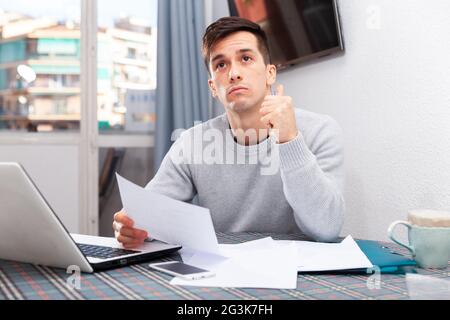 Jeune homme bouleversé compte budget familial on laptop Banque D'Images