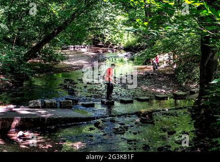 Une femme traverse des pierres sur une ford dans la rivière Banque D'Images