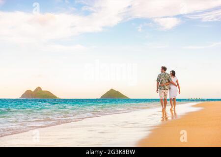 Hawaï vacances plage couple marchant au coucher du soleil luxe voyage destination lune de miel. Les jeunes mariés sont heureux sur la plage de Lanikai, Oahu, Hawaï. Banque D'Images