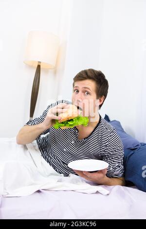Un seul homme mangeant au lit Banque D'Images