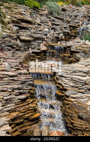 Plan vertical d'une petite cascade rocheuse qui coule dans une petite piscine Banque D'Images