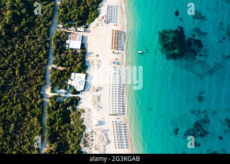 Vue d'en haut, vue aérienne sur une plage de sable blanc vide avec parasols de plage et turquoise, eau claire pendant le coucher du soleil. Banque D'Images