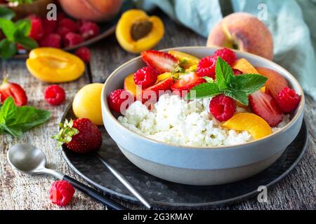 Petit-déjeuner ou dessert rustique d'été. Fromage caillé ou cottage servi avec des fruits d'été frais et des baies sur une table en bois. Banque D'Images
