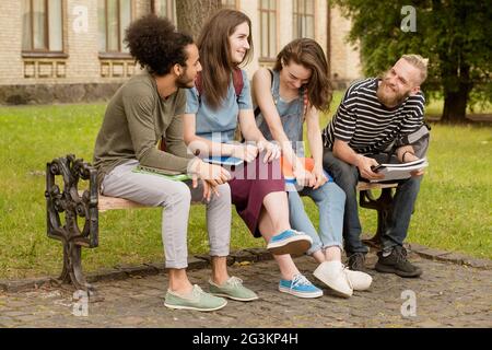 College friends sitting on bench in campus. Banque D'Images