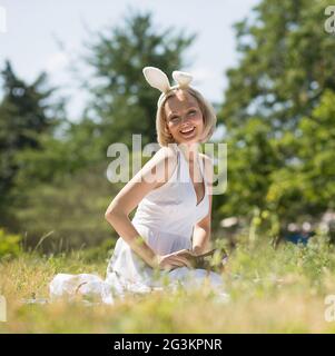 Heureux jeune mère portant des oreilles de lapin, de sourire à l'extérieur. Banque D'Images