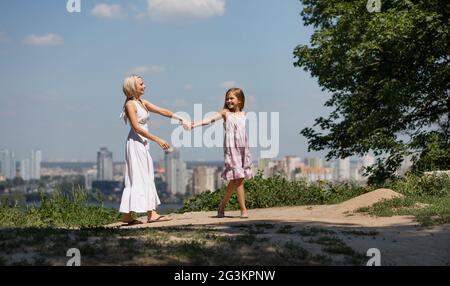 Mère et fille se tenir la main, marcher dans le parc de la ville. Banque D'Images