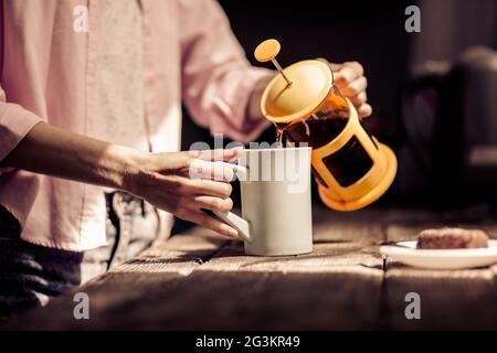 Vue rapprochée d'une femme qui verse du thé dans une tasse blanche. Banque D'Images