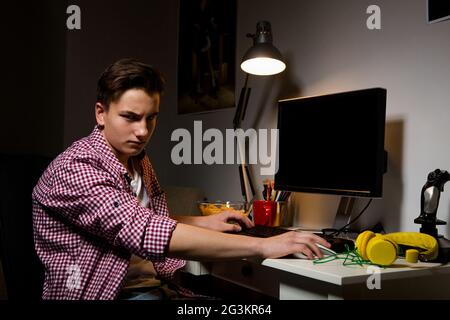 Adolescent malheureux assis à la table d'ordinateur. Banque D'Images