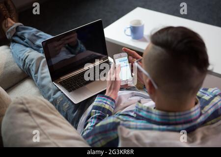 Vue arrière du travailleur indépendant travaillant avec un ordinateur portable sur le canapé. Banque D'Images