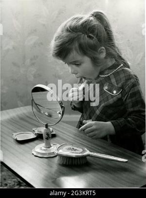 Cosmétiques, petite fille appliquant le rouge à lèvres, 22.4.1963, DROITS-SUPPLÉMENTAIRES-AUTORISATION-INFO-NON-DISPONIBLE Banque D'Images